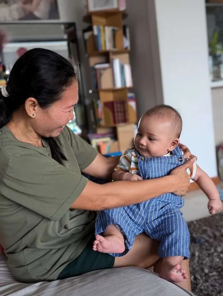 Une intervenante souriante portant un bébé